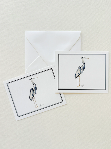 Two greeting cards with blue heron illustrations and a white envelope on a beige background