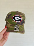 A camouflage baseball cap featuring a Georgia Bulldogs logo patch on the front and a '47 Clean Up sticker on the brim.