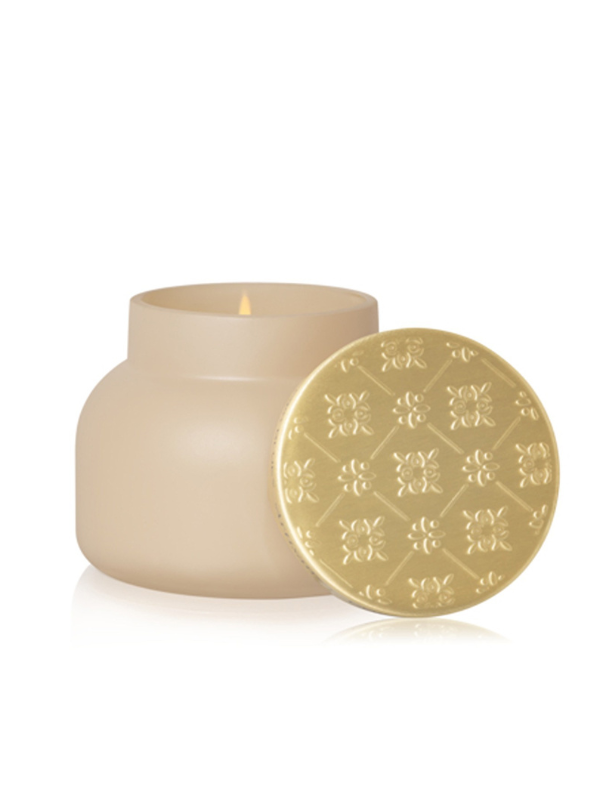 A matte beige candle jar with a matching round gold lid featuring an embossed floral pattern.