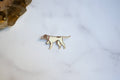 A small dog pin in gold-tone metal with a cream enamel fill