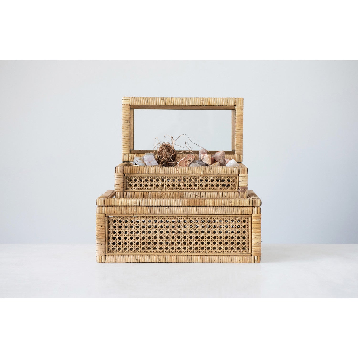 A large rattan storage box with a glass lid, displaying various items inside, placed against a neutral background.