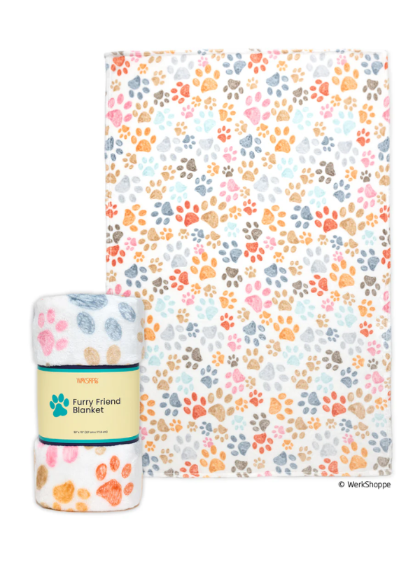 A multicolor paw print patterned blanket shown flat with a matching rolled blanket and paper band in front, on a plain white background. The paper band reads 'Furry Friend Blanket' and shows the WerksShop brand.