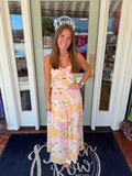 Blush pink and yellow floral maxi dress featuring spaghetti straps, a ruched bodice, a small keyhole cutout beneath the bust, and a flattering drop-waist silhouette with a flowing skirt.