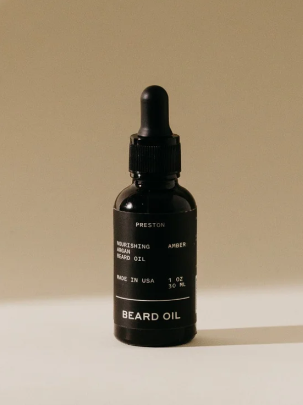 Black beard oil bottle with dropper on a beige background