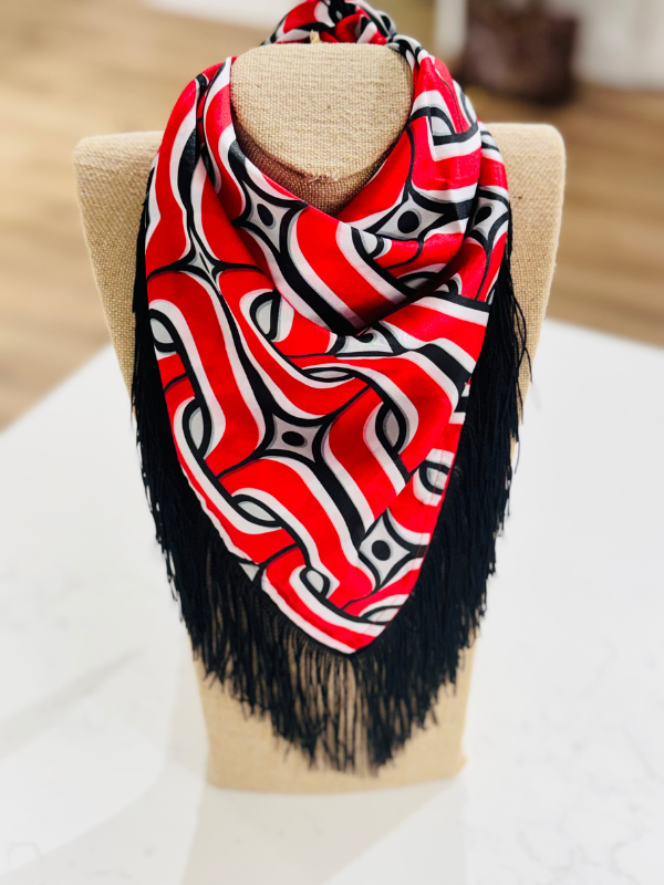 A red, black, and white patterned scarf with black fringe