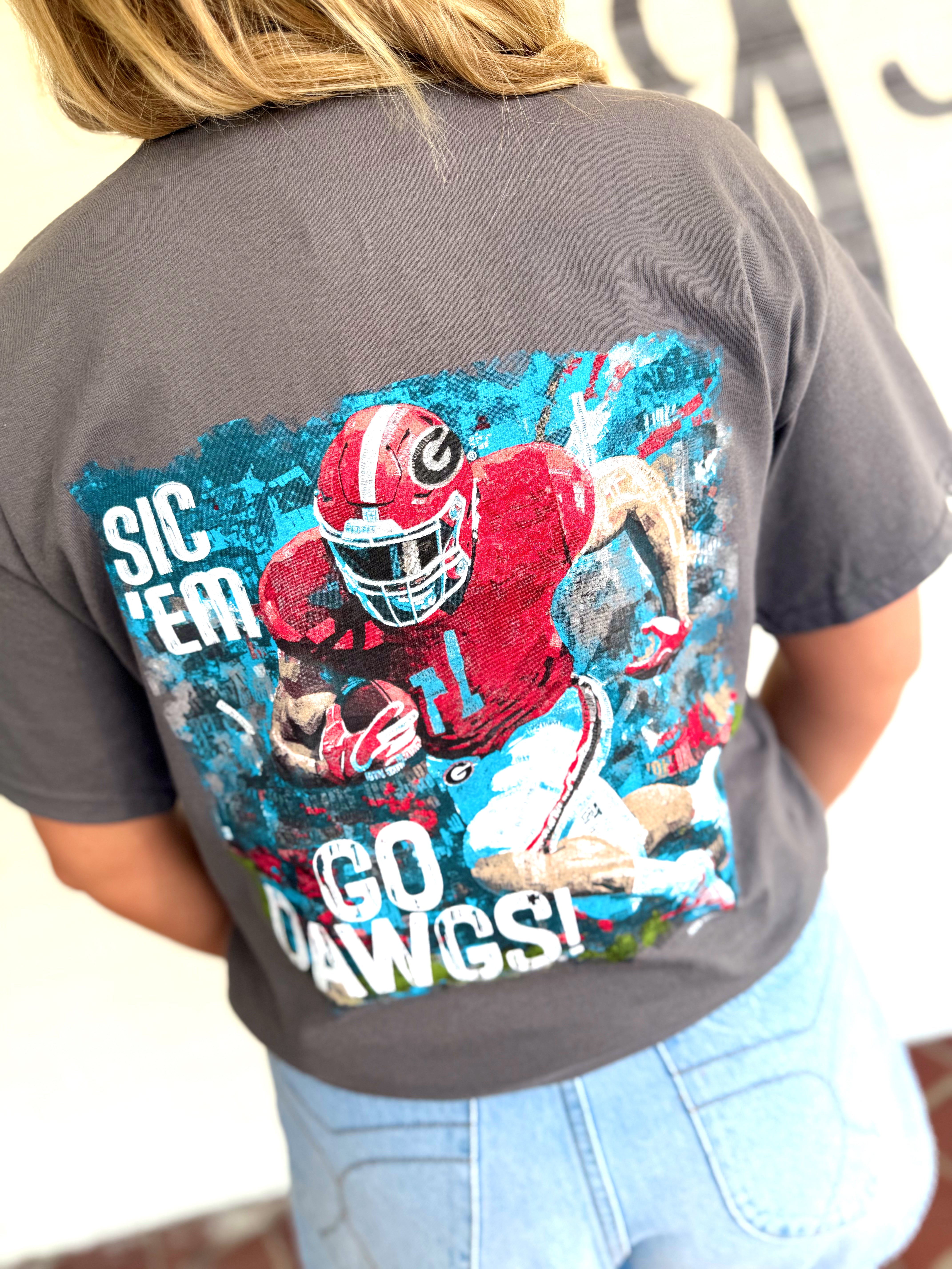 A dark gray t-shirt with a large graphic print of a football player in a red uniform and the text 'SIC 'EM GO DAWGS!'.