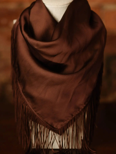 A dark brown fringed shawl or wrap draped on a white mannequin torso against a warm brown background.