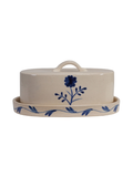 Cream-colored ceramic butter dish with a matching lid and saucer, decorated with a blue floral and vine pattern.