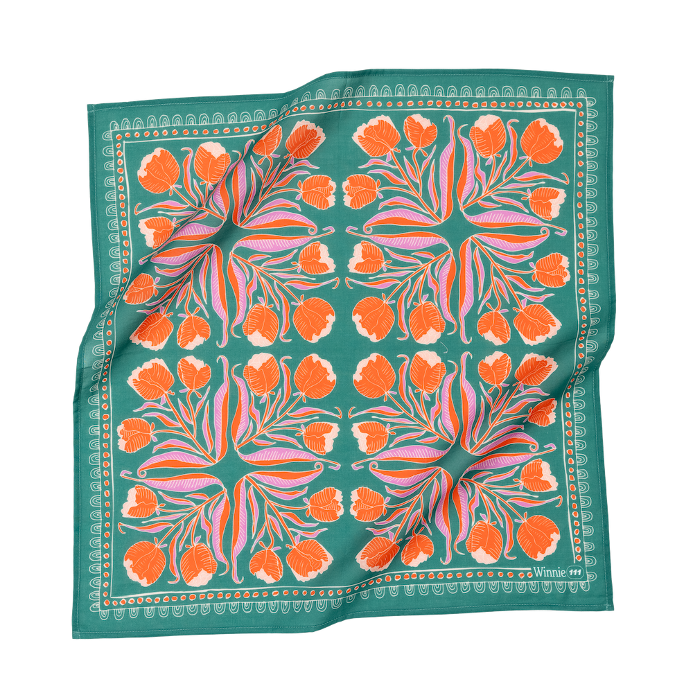 A teal bandana with orange and pink floral patterns, laid flat.