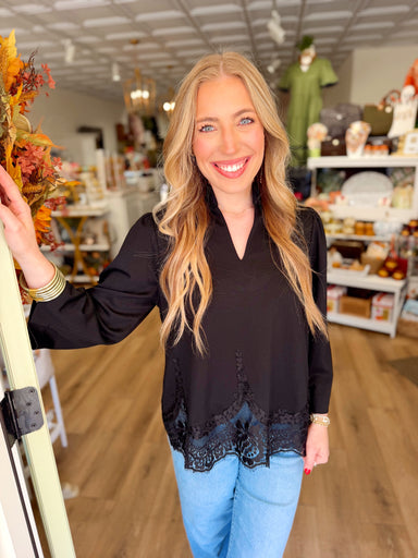 This top features a split neckline with a structured stand collar, three-quarter sleeves, and intricate tonal lace detailing along the hem.