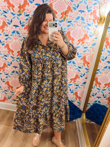 This midi dress features an allover vintage-inspired floral print in shades of navy, blue, golden yellow, and warm brown.