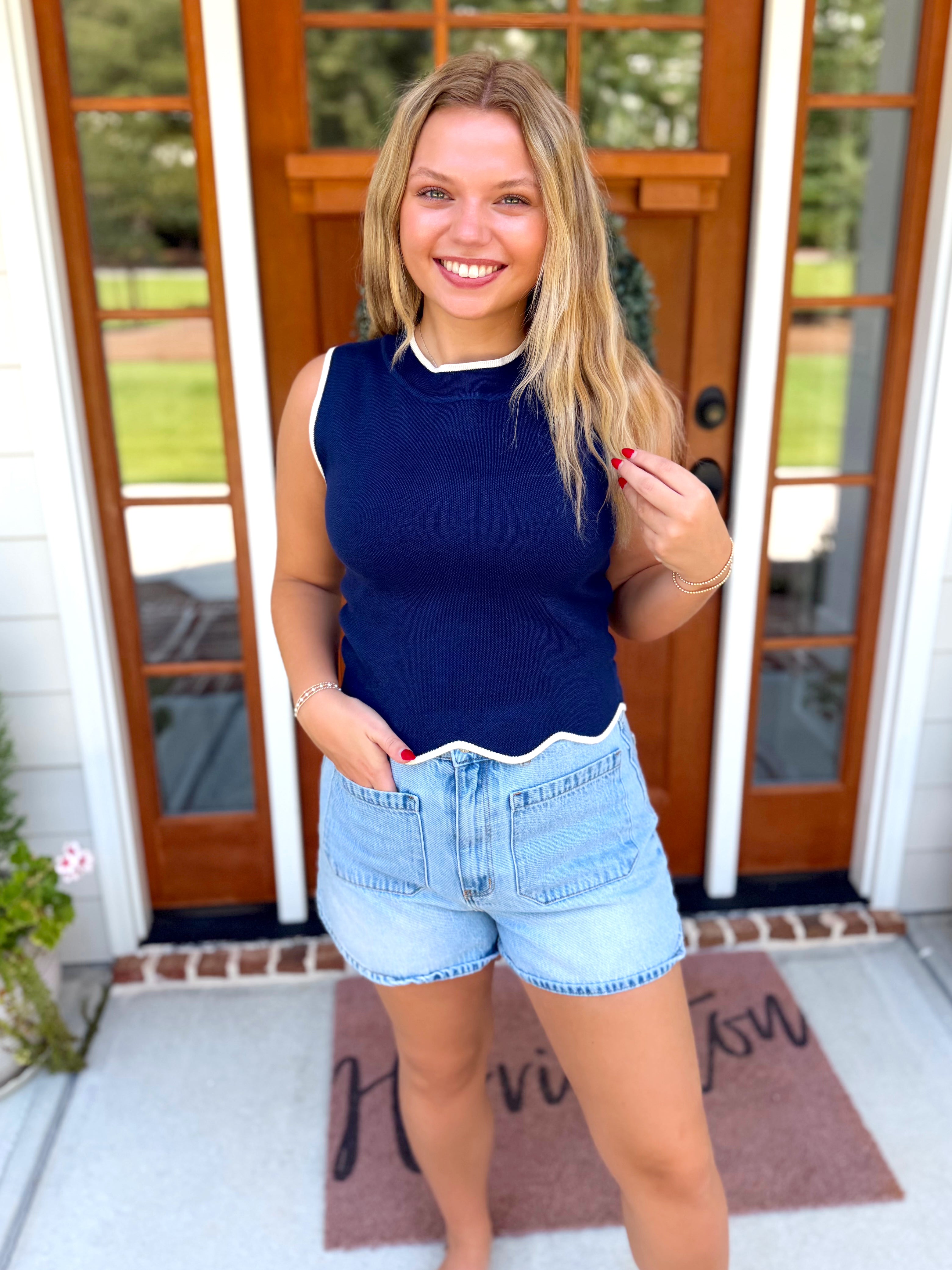 A sleeveless navy blue ribbed knit top with a white crew neck trim.