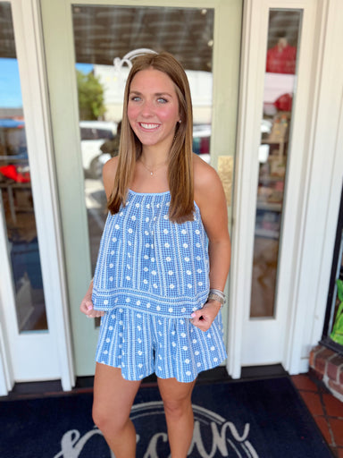 Blue patterned flowy shorts with white embroidered floral details and elastic waistband.
