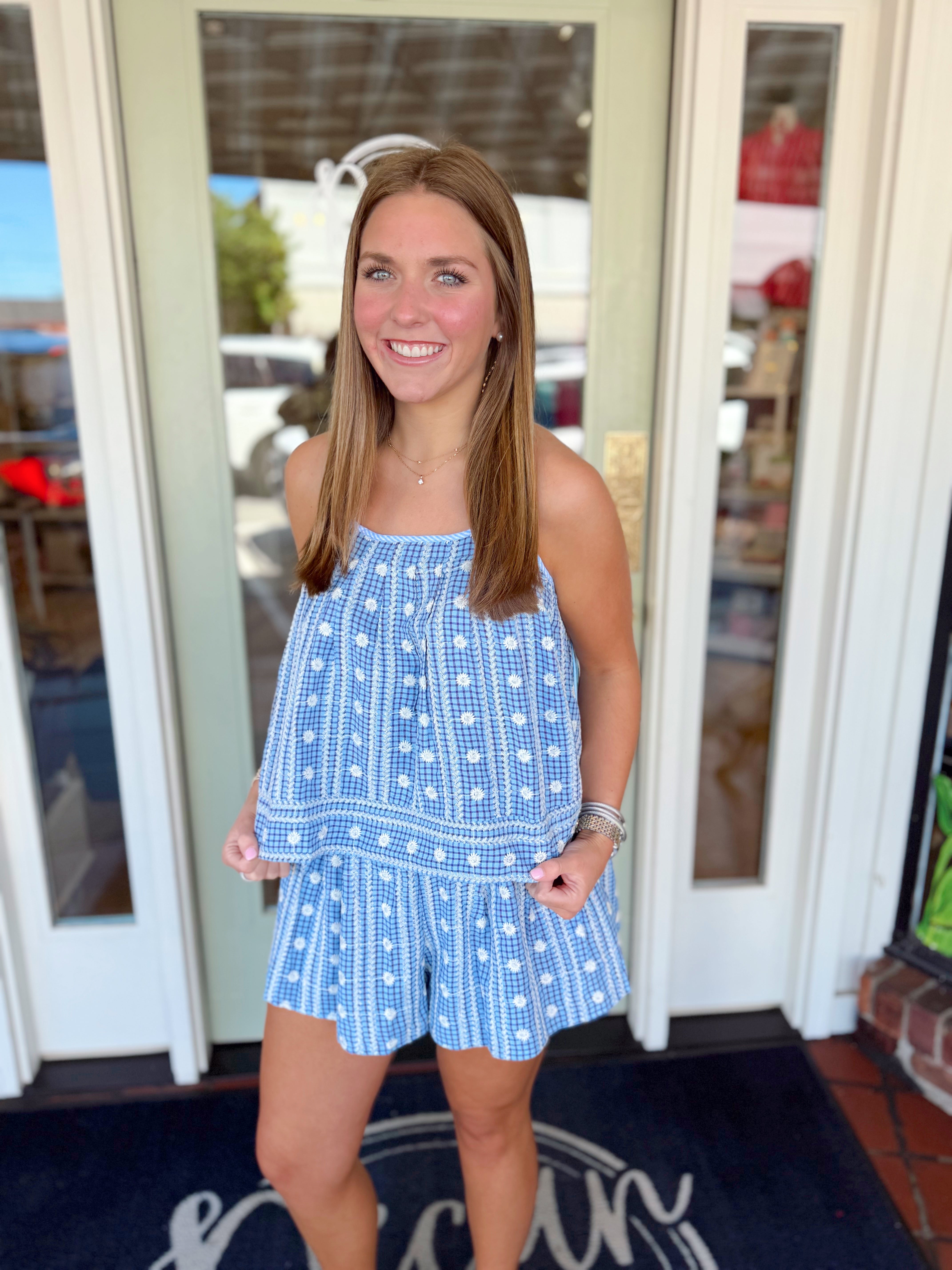 Blue patterned flowy shorts with white embroidered floral details and elastic waistband.

