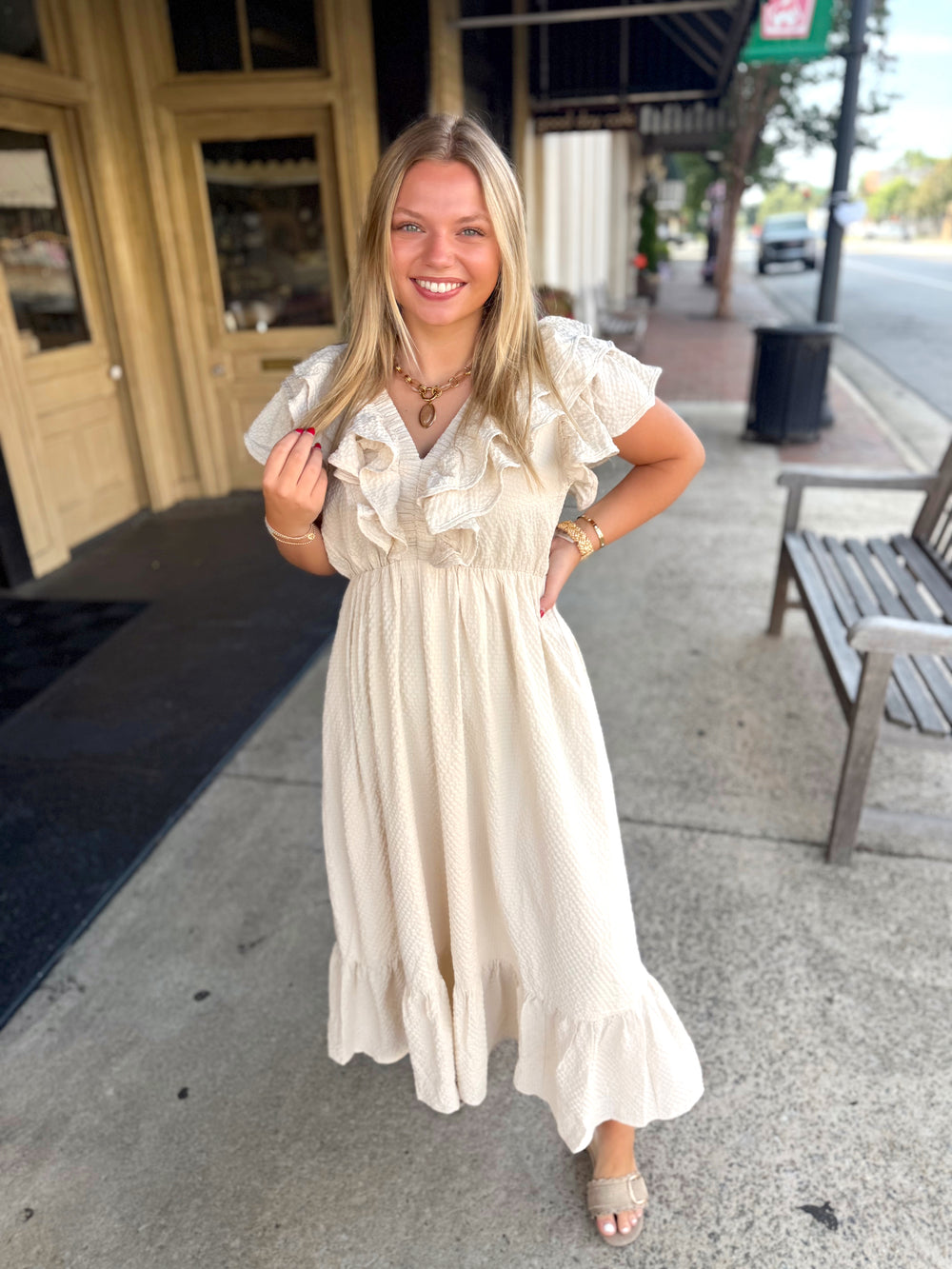 Cream-colored, tiered midi dress with ruffled short sleeves and a gathered waist. 