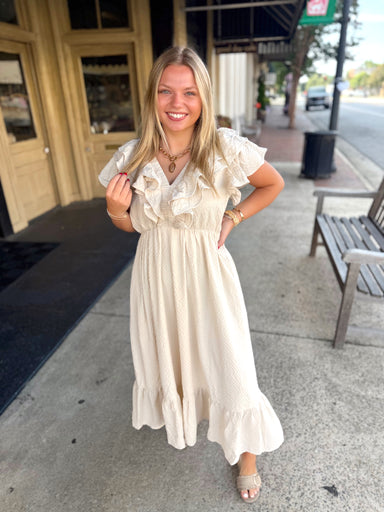 Cream-colored, tiered midi dress with ruffled short sleeves and a gathered waist. 
