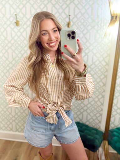  This top features soft tan and ivory stripes with subtle textured detailing throughout, a split neckline, and a statement tie-front hem. 
