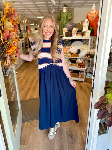 A navy blue maxi dress with a cream and navy striped bodice and a twisted waist detail. 