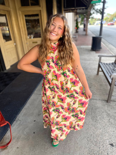 A sleeveless high-neck maxi dress with a vibrant pink, green, and orange floral pattern