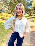 This champagne satin blouse features a soft, lustrous finish with a feminine ruffled stand collar, relaxed silhouette, and three-quarter sleeves.