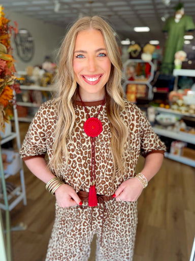  This top features an allover leopard print in warm brown and cream tones with a textured knit finish. 