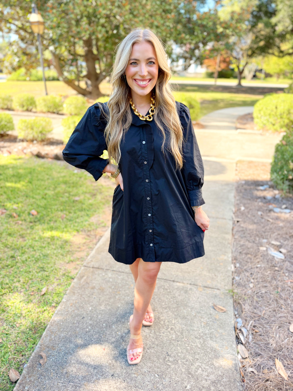  This dress features a ruffled high neckline with front button detailing, statement puff sleeves, and a self-tie waist at the back for a flattering finish. 