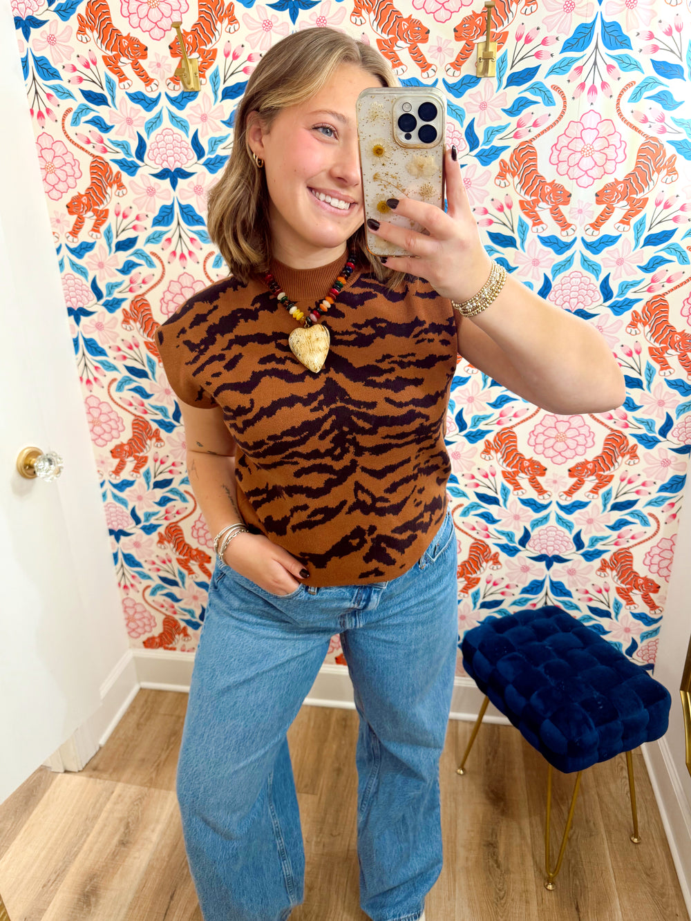 This camel and chocolate tiger print sweater top features a fitted silhouette with cap sleeves and a ribbed mock neckline.