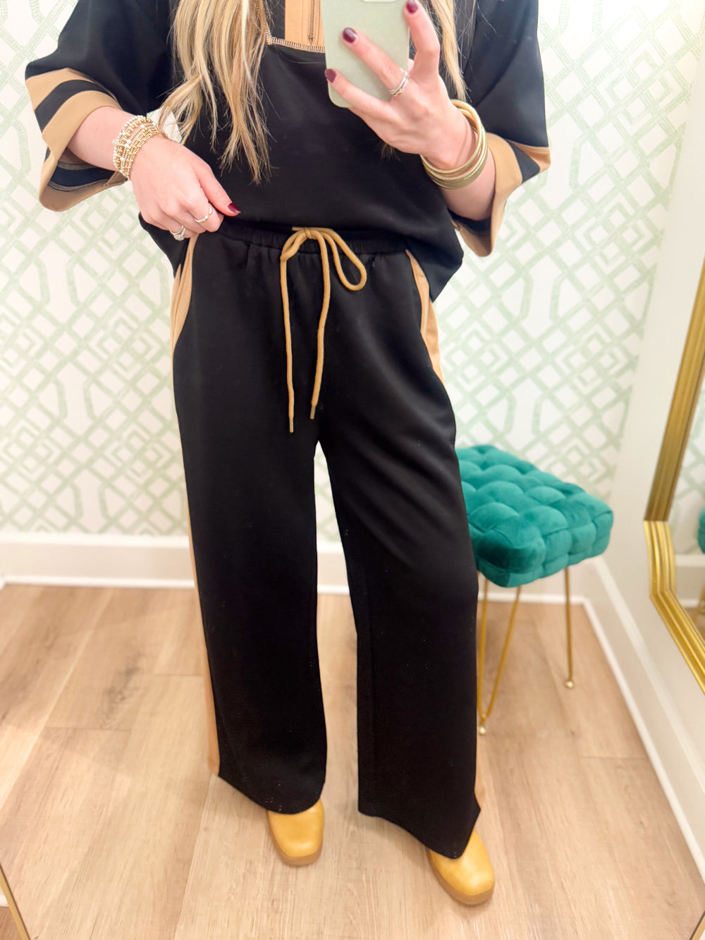 These pants feature a classic black body with warm camel contrast accents along the sides and pockets, plus a coordinating camel drawstring at the waist.