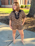 This lightweight knit top features a classic leopard print with a stand collar, partial zip front, and contrast trim for a sporty, elevated finish.