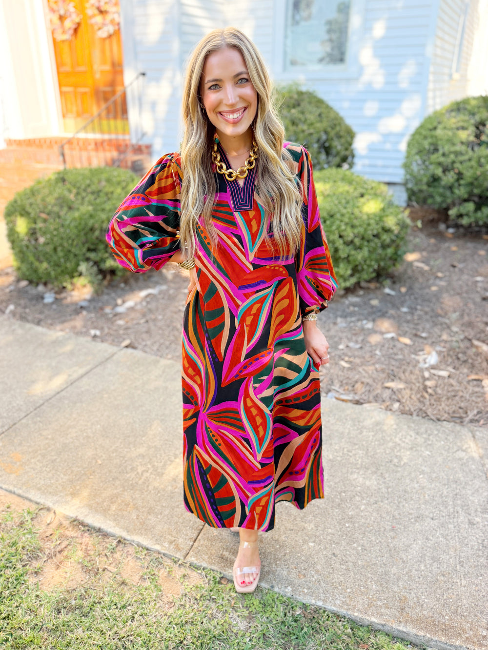 This midi dress features a bold multicolor abstract print, flattering V-neckline, and flowy long sleeves.