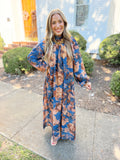 This maxi dress features a rich blue base with warm rust and brown florals.