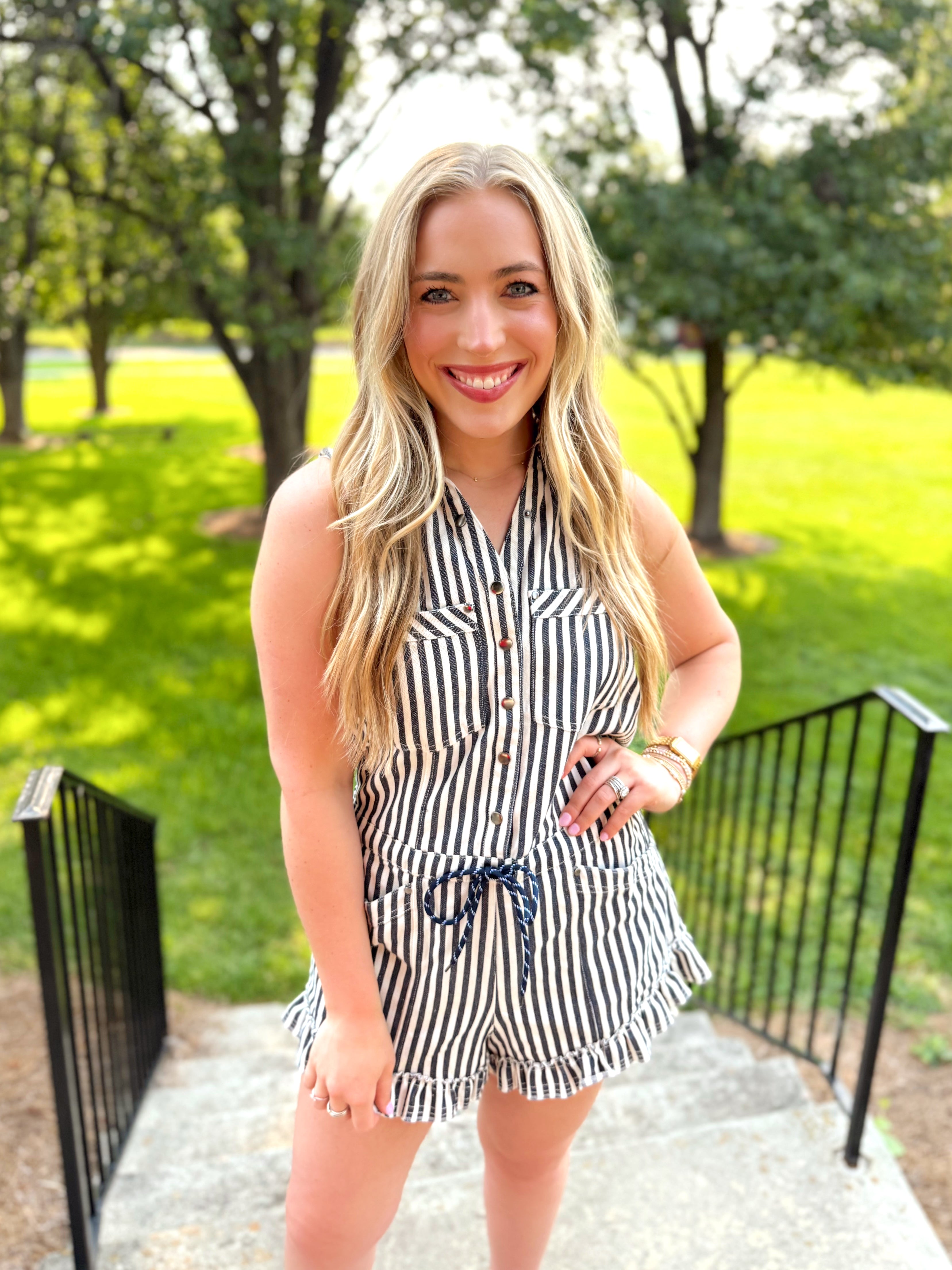 Navy and cream striped sleeveless romper with ruffle detail on the bottom.