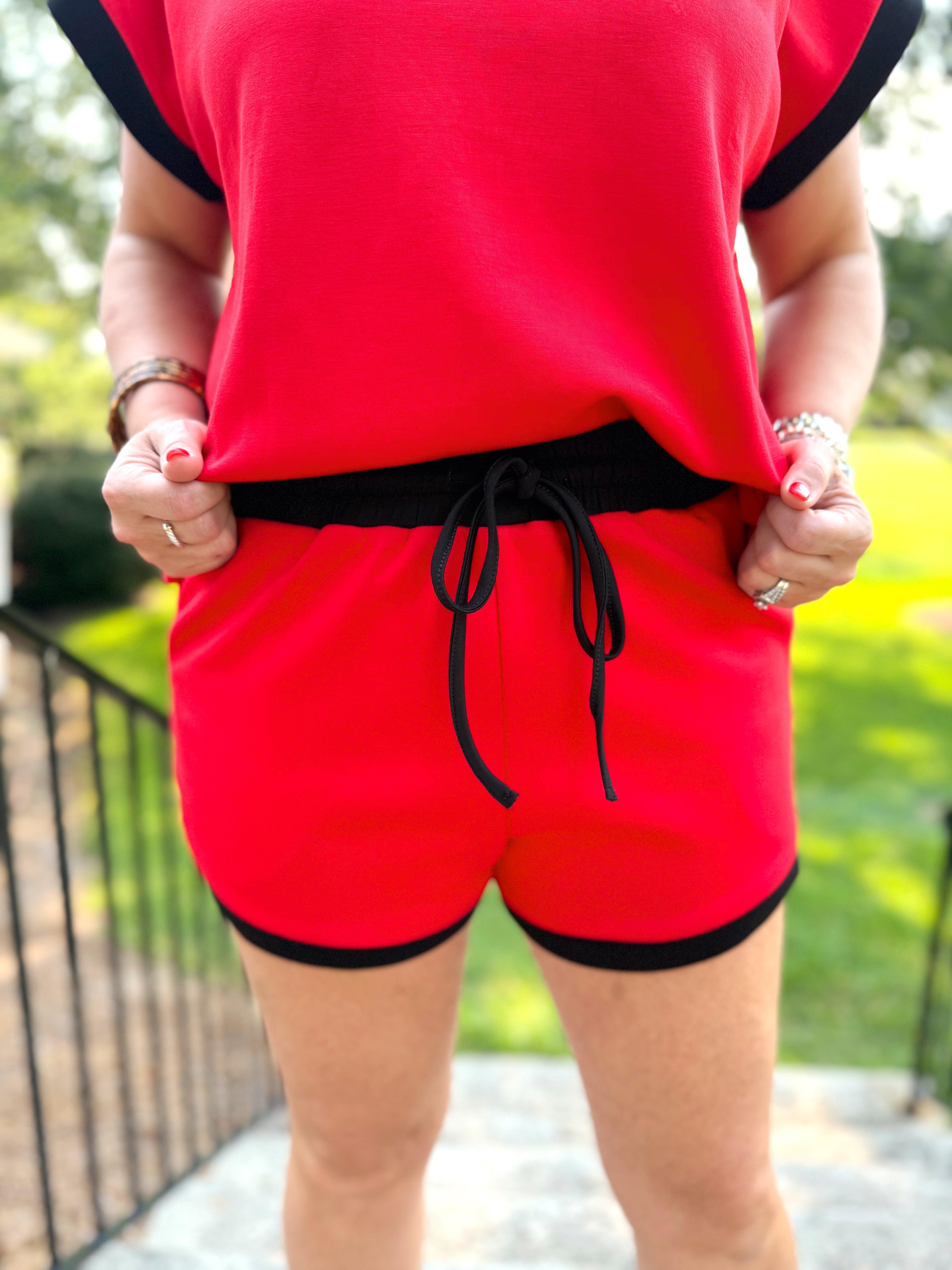 Red shorts with a black drawstring waist.
