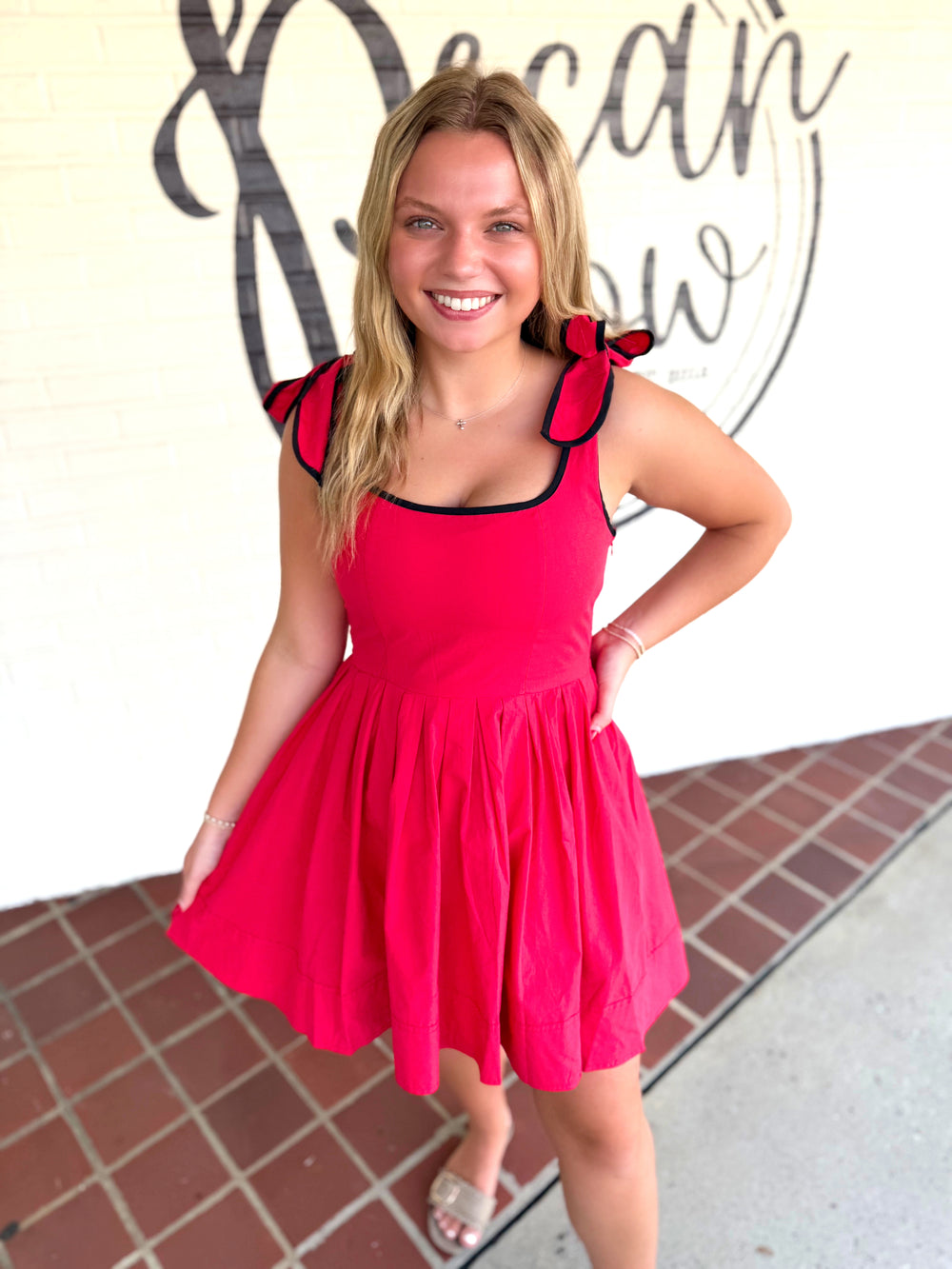 A red sleeveless dress with black trim and ruffled shoulder details