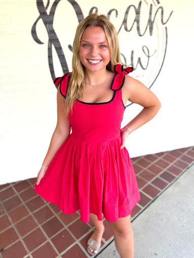 A red sleeveless dress with black trim and ruffled shoulder details