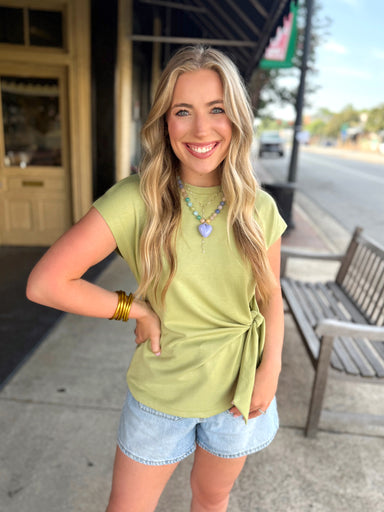 Light olive green short-sleeve top with a side tie detail.