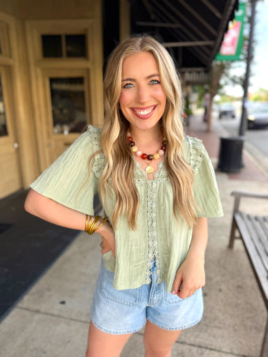 Light sage green short-sleeve blouse with lace trim.