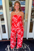 Strapless coral-red top featuring a blush tropical leaf print, elastic neckline, and relaxed flowy silhouette.