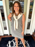 A sleeveless black and cream striped dress with a cream neck scarf.