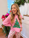 pink sweatshirt with a Christmas tree and a lady decorating it