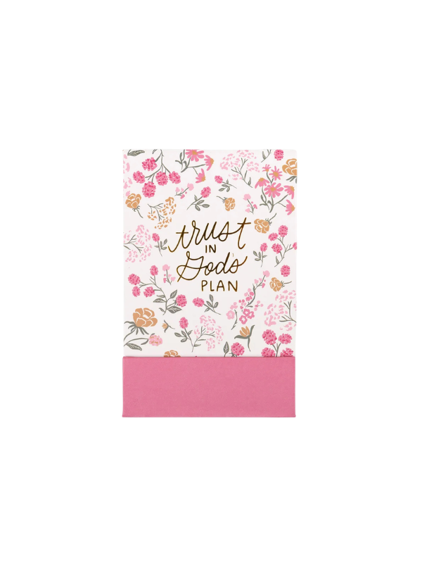 A floral planner or journal cover with the words 'trust in God's plan' in gold script, featuring pink and orange flowers on a white background with a solid pink band at the bottom.