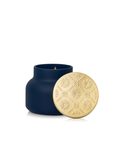 A navy blue glass candle jar with a gold-toned lid featuring an embossed floral pattern