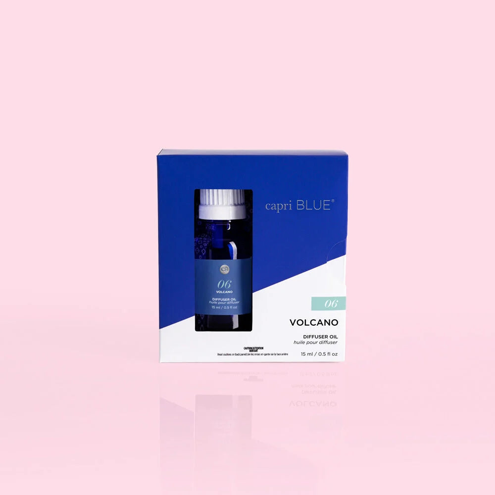 A boxed diffuser oil set on a pale pink background. The product packaging is blue and white, and a small dark glass diffuser bottle with a white cap is visible through a window on the front.