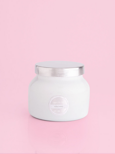 A volcano scented white candle jar with a silver lid by capri blue