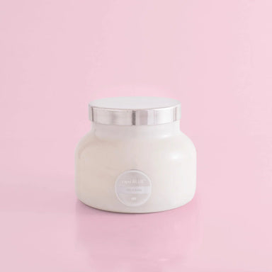 A volcano scented white candle in a white jar with a silver by capri blue.