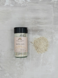 Bottle of Finch + Fennel Kettle Corn Seasoning beside a pile of seasoning blend, featuring cane sugar, sea salt, brown butter, and vanilla bean for sweet-and-salty gourmet popcorn.